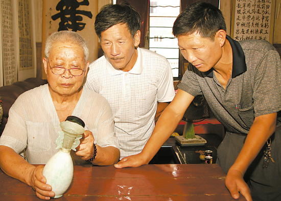 卜茂兰(左)用放大镜观察一件水晶琉璃兽耳瓶 张建成 摄