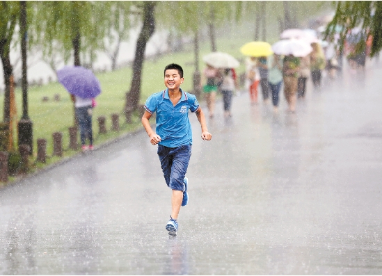 图为一位少年在雨中奔跑.     本报记者 魏志阳 摄