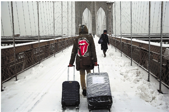 3月5日,在美国纽约,一名男子拉着行李箱走在风雪中.