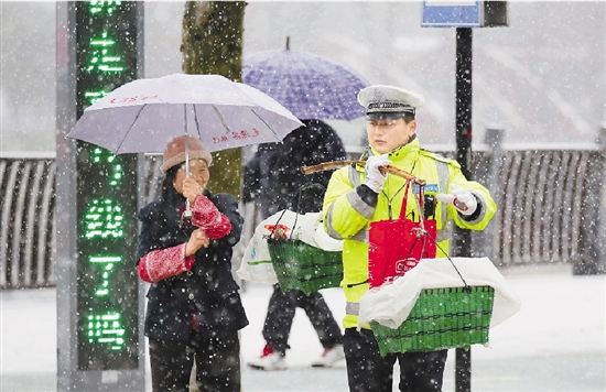 淳安境内路面出现积雪,值勤交警在风雪中热心帮助路人.