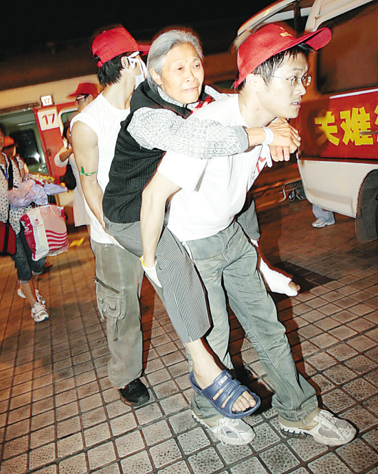 志愿者背着伤员上救护车.梁臻 摄