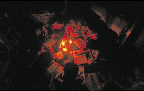 7月31日,在印度加尔各答,一位教师(中)在烛光下向学生授课.